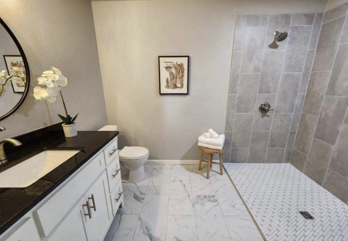 Black vanity with marble tile floor bathroom remodel by Lorett's Remodeling and Construction in Tulsa, OK